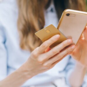 Close-up of a woman shopping online using a smartphone and credit card.